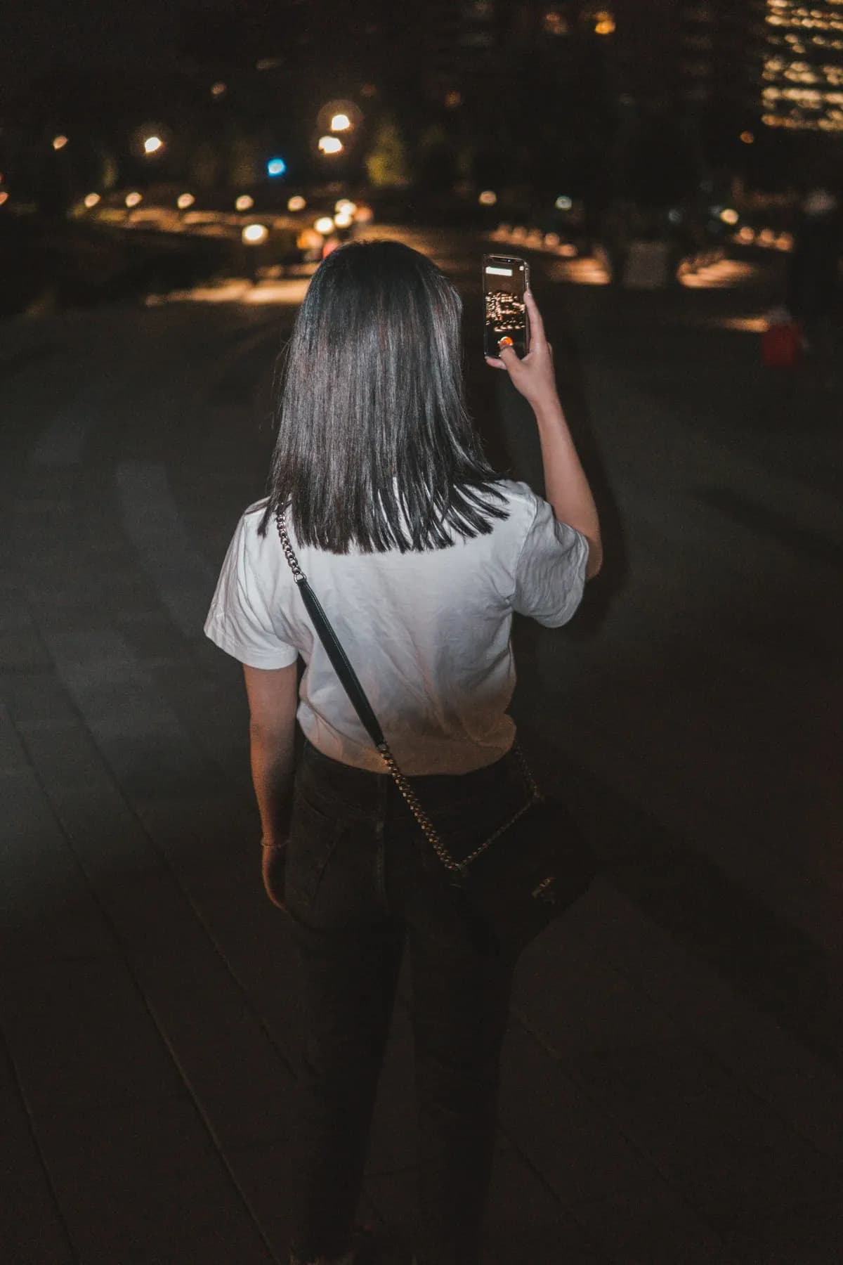 A woman using her smartphone on a street at night